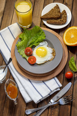 English Breakfast: fried egg, juice, cherry tomatoes, lettuce, grain bread, sauce, top view.