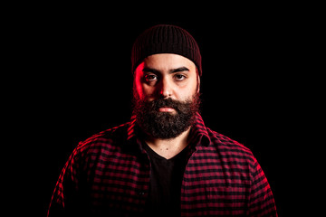 Bearded hipster in studio portrait with two colored red lights from behind
