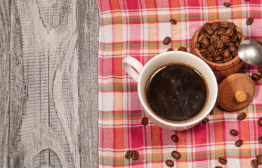 White cup with the remains of coffee on a colored napkin and a barrel with coffee beans