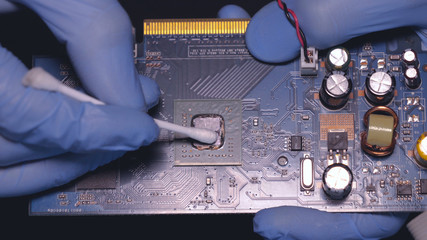 Master in blue rubber gloves, repairing the board, chip, cleaning the video card, soldering a spot,...