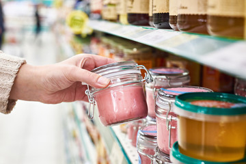 Hand with can of honey souffle with raspberries in store