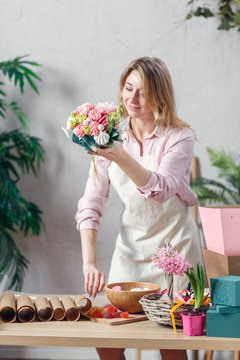 Image of florist holding bouquet in hands at table with marmalade, marshmallow, boxes, paper