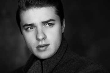 Close-up portrait of a handsome young man. The man's gaze is directed to the side. Black and white photography