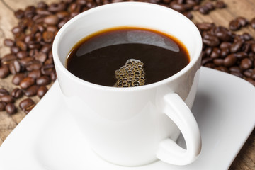 Eine Tasse mit frischem schwarzem Kaffee und Kaffeebohnen