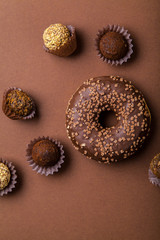 Chocolate donuts with chocolate truffles on brown background. Monochromatic concept.