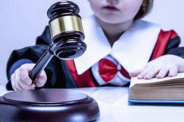 Portrait of serious child girl judge (lawyer) makes a decision. Humorous photo.(letter of law, strict law, justice concept)