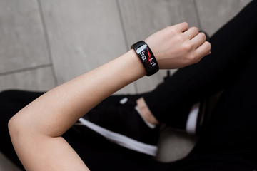 A woman's hand with a smart watch. Close-up. Black sportswear. The lotus position. Wooden floor.