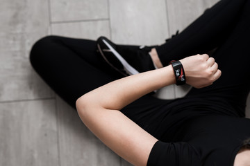 A woman's hand with a smart watch. Close-up. Black sportswear. The lotus position. Wooden floor.