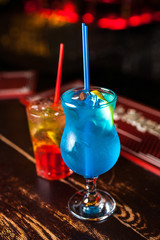 Two different cocktail on the bar. Colorful blue lagoon and orange cocktail.