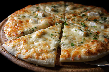 Pizza four cheeses on a wooden board