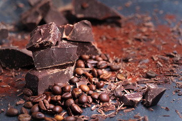 Broken dark chocolate, cocoa powder and coffee beans on a wooden table