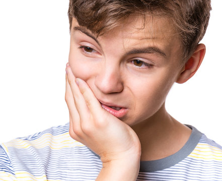 Closeup portrait teen boy with sensitive tooth ache crown problem touching outside mouth with hand. Child toothache. Negative human emotion, facial expression feeling reaction. 