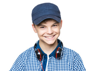 Modern teenager enjoys the music in headphones. Youth culture. Handsome young boy with cap isolated on white background and smiling. 