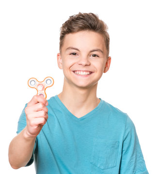 Young teen boy holding popular fidget spinner toy - close up portrait. Happy smiling child playing with Spinner, isolated on white background.