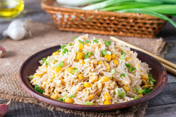 Asian fried rice with eggs and corn on the plate on wooden background