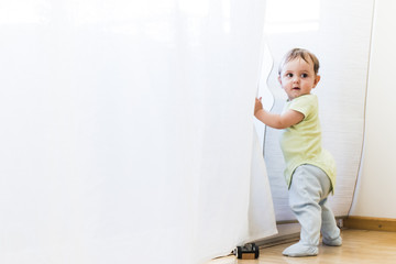 baby playing with white curtains