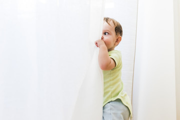 baby playing with white curtains