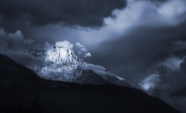 Scenic landscape with mountain peak Annapurna in overcast dramatic cloud sky.