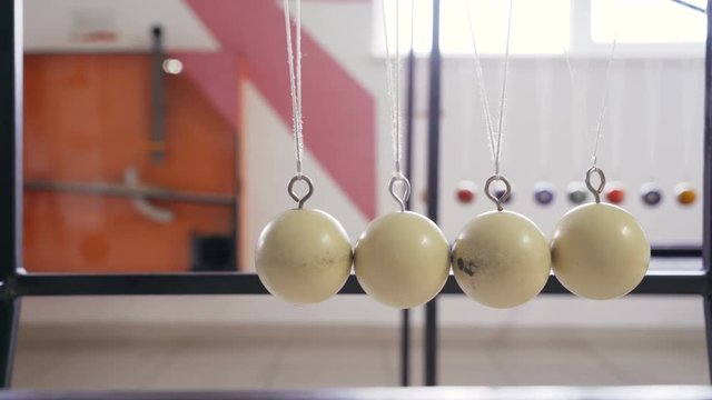Hand holding a pendulum ball. Newton's cradle