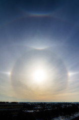 Varoious sun halos arc appearing in the winter sky in the city with birds flying. Rare natural phenomenon. Upper tangent arc.