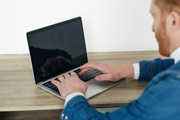 Redhead man typing on laptop keyboard