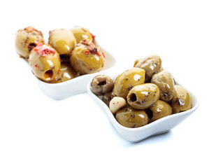 Spiced green olives in oil isolated on white .