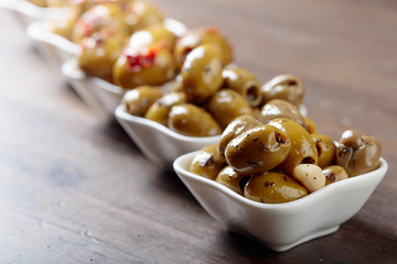 Spiced green olives in oil on a wooden table.