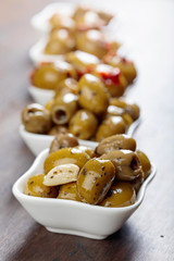 Spiced green olives in oil on a wooden table.