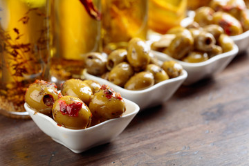 Spiced green olives and bottles with olive oil .