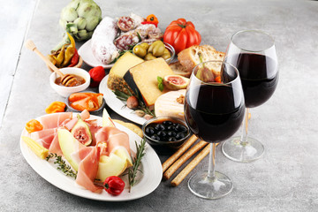Italian antipasti wine snacks set. Cheese variety, Mediterranean olives, pickles, Prosciutto di Parma with melon, salami.