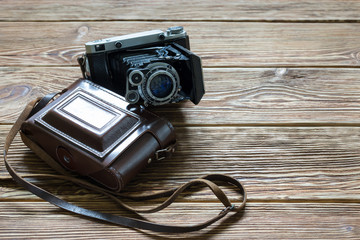 The old medium format rangefinder camera and leather case. Wooden background.