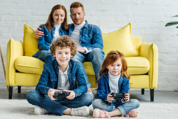 Children playing video game while parents sitting on sofa