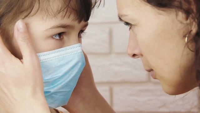 A parent with a sick child. A little girl in a medical mask looks at mother.