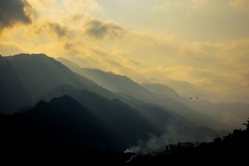 Impressive sun rise / sun set view by sun light shining over mountains, seeing layers of mountains in shadow,