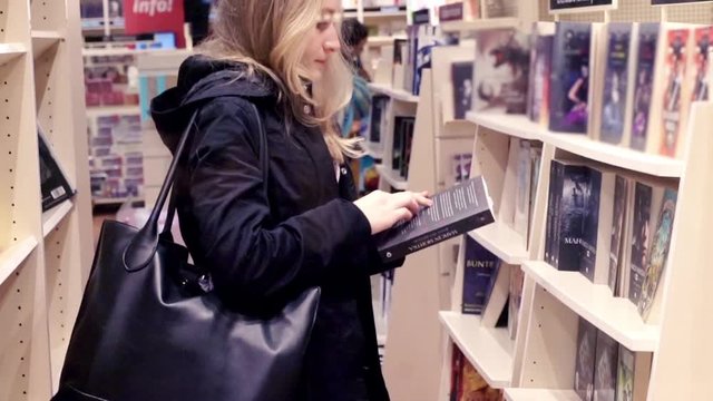 Young woman looking book in bookstore
