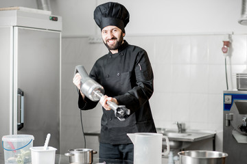 Funny portrait of a chef cook standing with blender in the professional kitchen during the process...