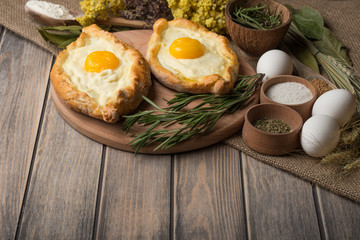 Khachapuri on a wooden texture with spices. Traditional Georgian cuisine.