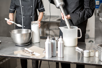 Chefs mixing ingredients for ice cream production in the professional kitchen. Close-up view wuth no face