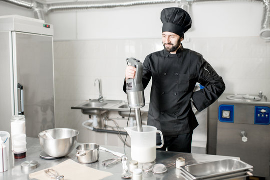 Portrait of a chef cook mixing with blender milk for ice cream production in the professional kitchen