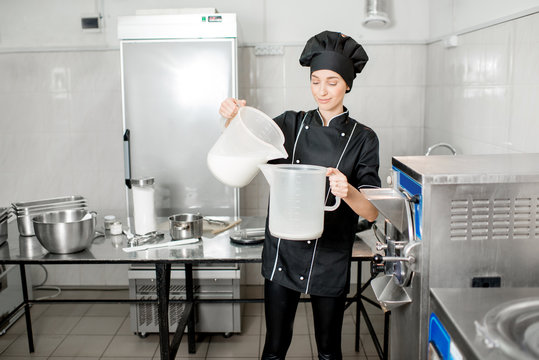 Young woman chef pouring milk prepairing basis for ice cream production in the kitchen