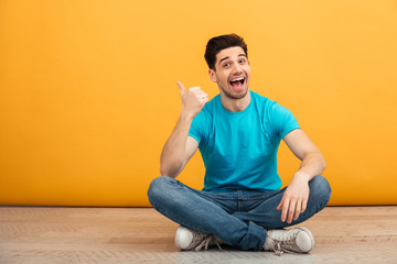Portrait of a cheerful young man pointing finger