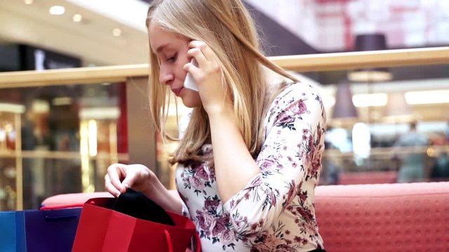 Young, happy woman talking on cellphone at shopping mall 
