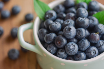 Fresh blueberries heap in ceramic bowl in close up view macro concept with copy space on wood table for background. Blueberry is healthy and delicious fruits which have high antioxidant and vitamin C.