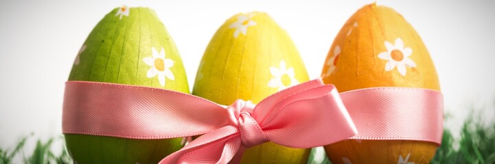 Three easter eggs wrapped in pink ribbon