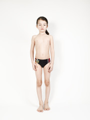 Sad and lonely barefoot kid boy in swimming trunks, isolated on white