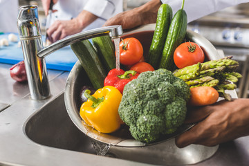 cropped image of african american chef washing vegetables at restaurant kitchen