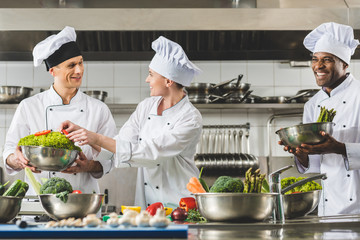 cheerful multicultural chefs cooking at restaurant kitchen