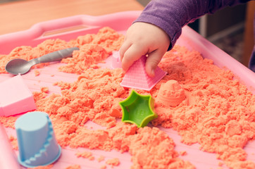 The hands of a child playing with kinetic sand