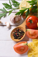 Food ingredients dry pasta and Italian spaghetti with herbs vegetables, on white wooden table, copy space, top view.