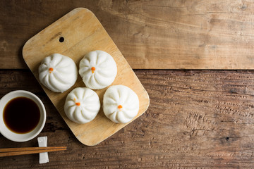 top view of steamed chinese bun (baozi) on cutting board served with soy sauce, copy space for...